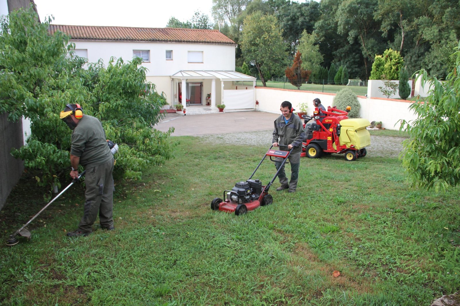 Entretien d'espaces verts : ouvriers passant la tondeuse, débroussaillant un jardin